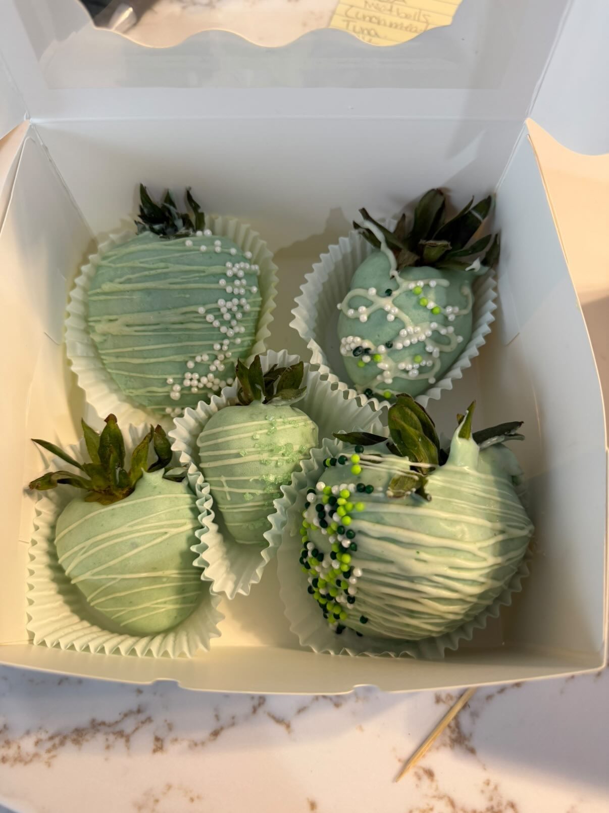 Sage-green dipped strawberries drizzled and finished with white and green pearls.