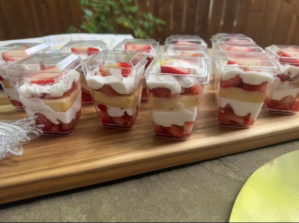 Strawberry shortcake dessert cups layered with cream, sponge cake, and fresh strawberries.