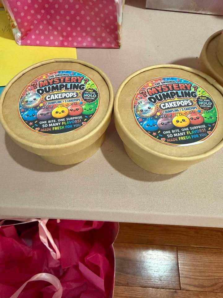 Two kraft tubs of Mystery Dumpling cake pops with the shop's holographic label.