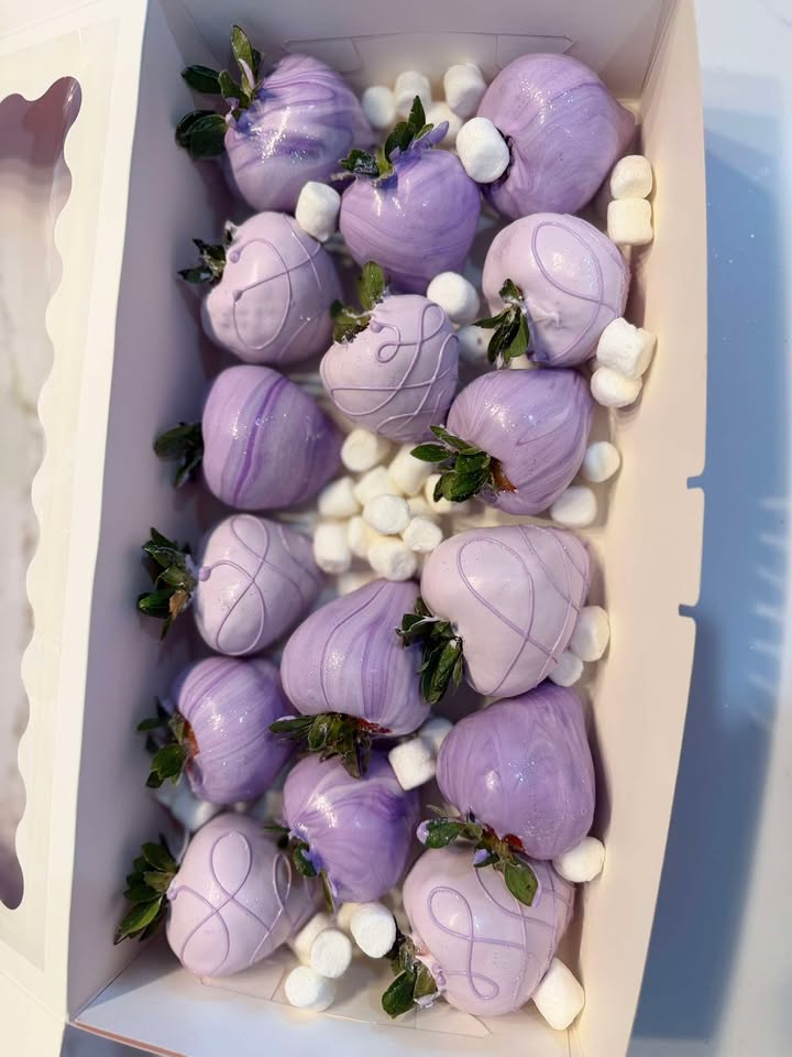 Lavender chocolate-covered strawberries with white drizzle and marshmallows in a long gift box.