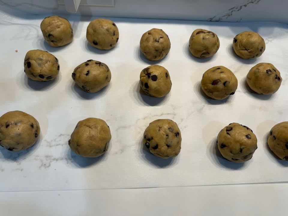 Chocolate chip cookie dough portioned onto a parchment-lined tray.